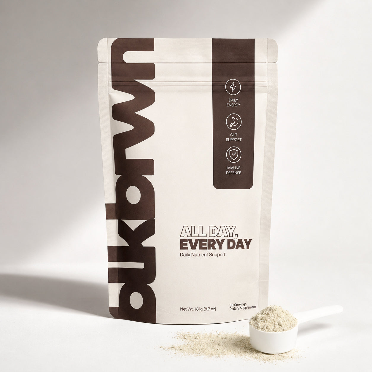 A woman rests her head on her hand, posing behind a white pouch of blkbrwn supplement.